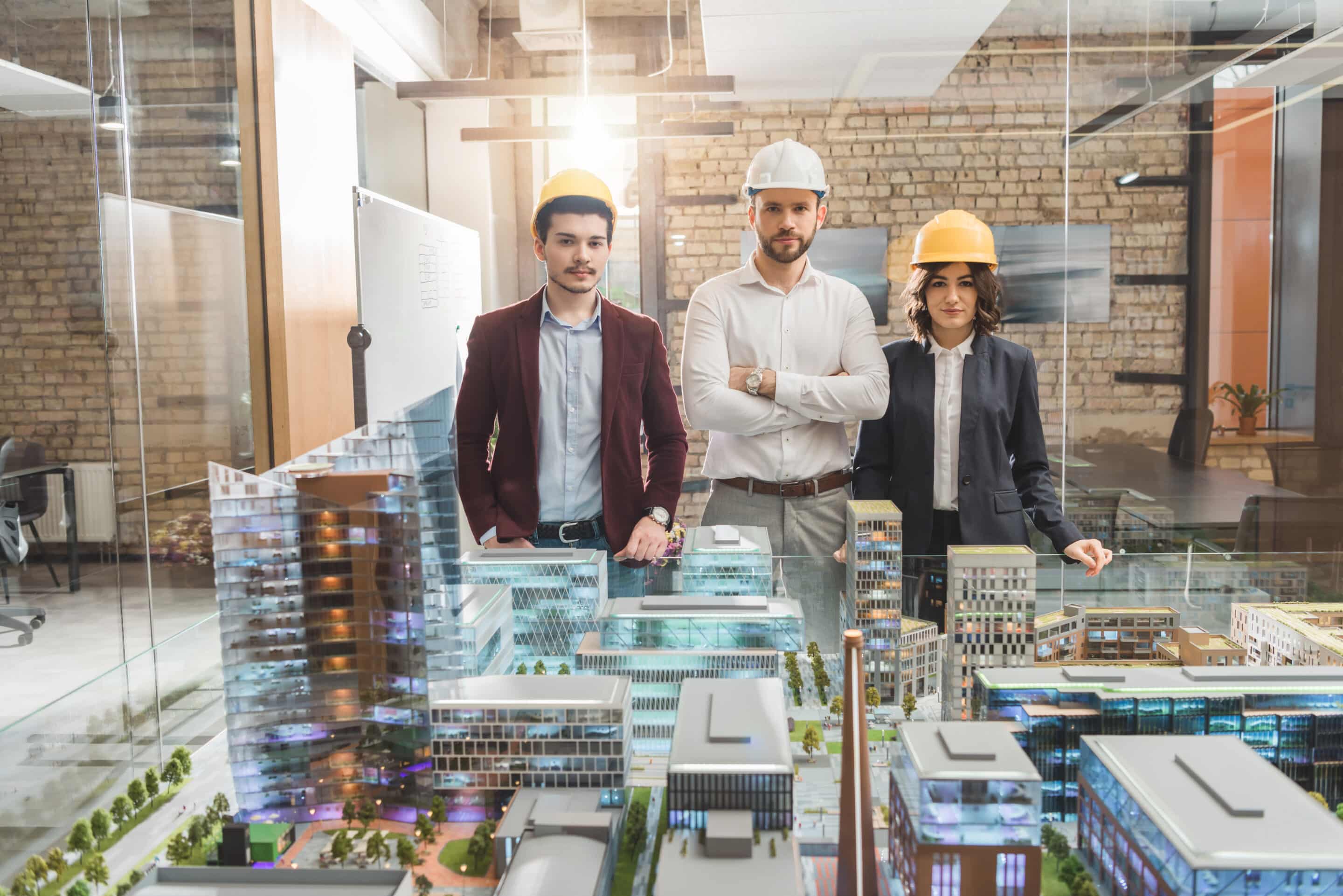 team of architects in hard hats in front of miniature town model at office Normes BIM